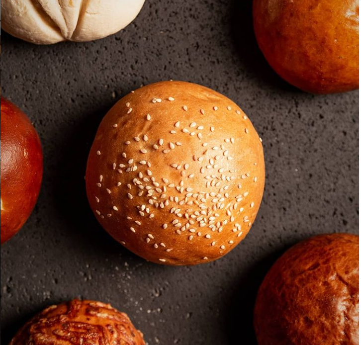 Moist, fluffy, flavorful artisanal burger buns by Panito on a cutting board, ready for grass-fed beef.